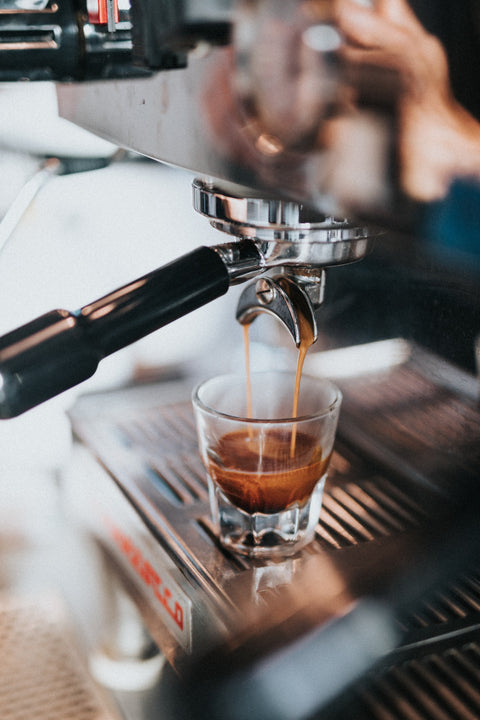 Ein Espresso Shot läuft langsam aus einer Siebträgermaschine in ein Glas